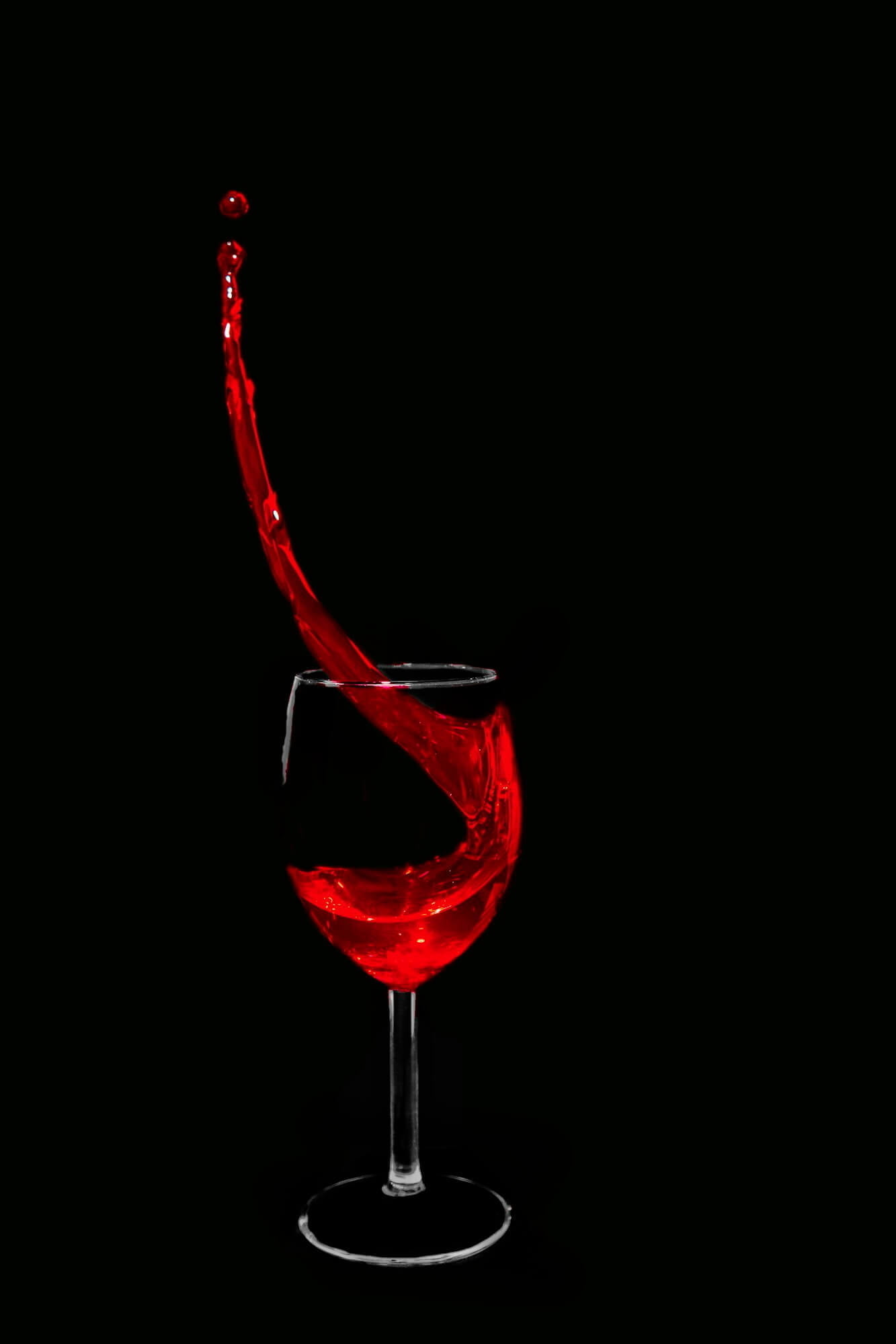 Closeup of wine splash in the wine glass on black background